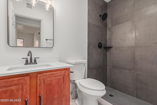 bathroom with vanity, toilet, and a tile shower