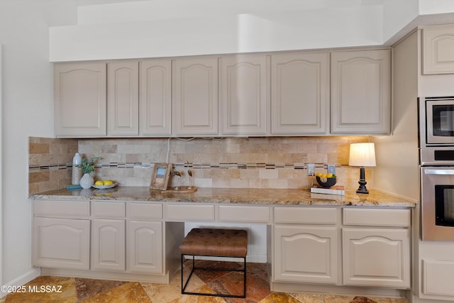 kitchen featuring white cabinets, appliances with stainless steel finishes, light stone counters, and backsplash