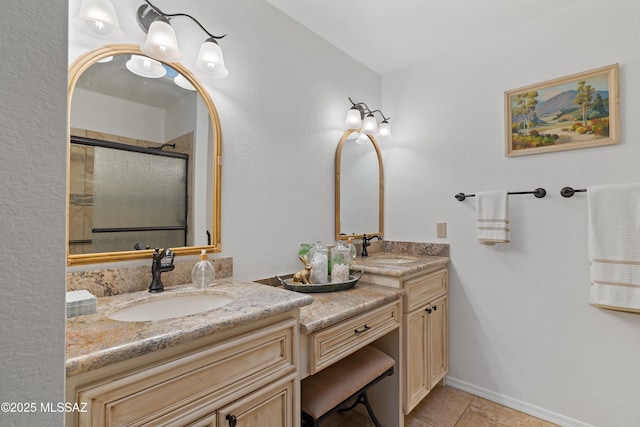 bathroom featuring a shower with shower door, vanity, baseboards, and tile patterned floors