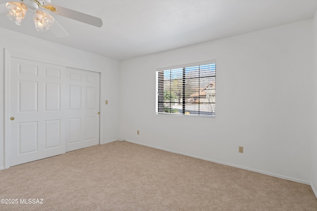 unfurnished bedroom with baseboards, a closet, a ceiling fan, and light colored carpet