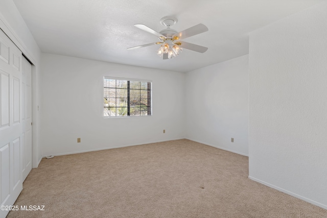 unfurnished bedroom featuring light carpet, ceiling fan, baseboards, and a closet