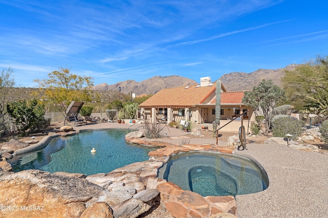 view of swimming pool featuring a fenced in pool, an in ground hot tub, a mountain view, and a patio