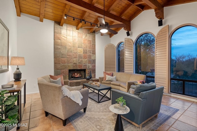 living room with a fireplace, beam ceiling, wooden ceiling, light tile patterned floors, and rail lighting