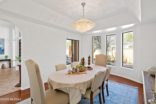 dining area featuring dark hardwood / wood-style floors, a chandelier, and a tray ceiling