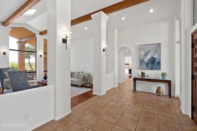 hallway featuring lofted ceiling with beams, decorative columns, and light tile patterned floors