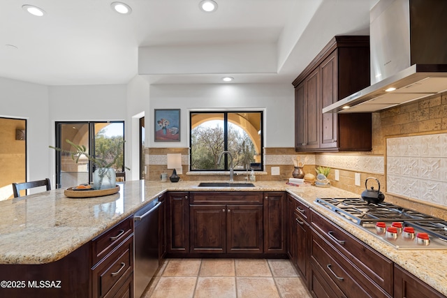 kitchen featuring appliances with stainless steel finishes, wall chimney range hood, a breakfast bar, sink, and kitchen peninsula