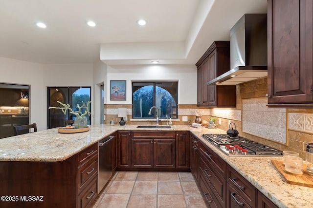 kitchen with kitchen peninsula, sink, tasteful backsplash, appliances with stainless steel finishes, and wall chimney exhaust hood