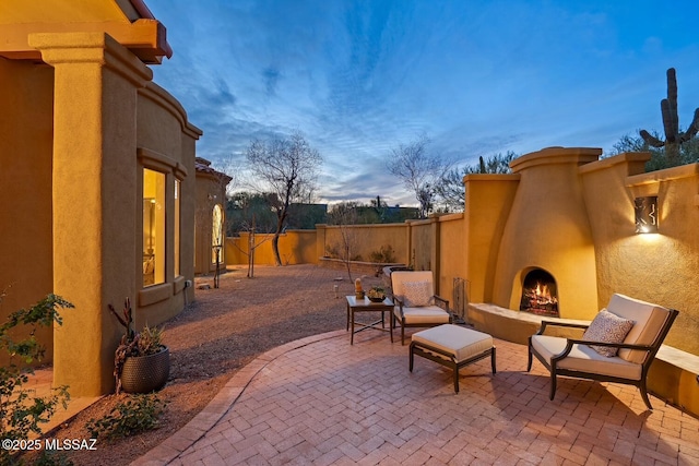 patio terrace at dusk with an outdoor fireplace