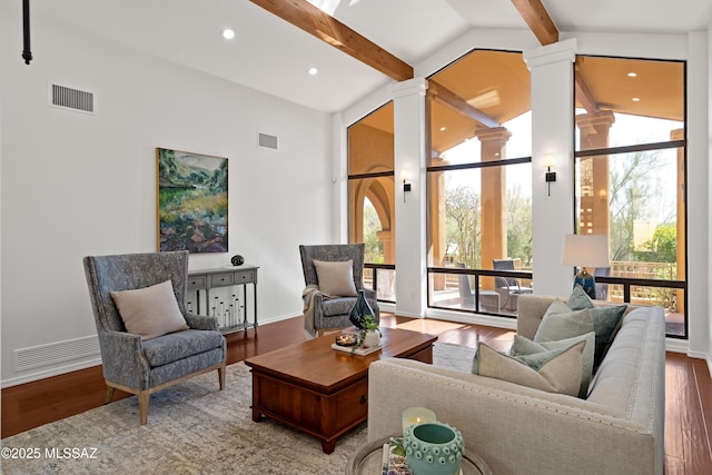 living room with ornate columns, high vaulted ceiling, beamed ceiling, a wall of windows, and hardwood / wood-style floors