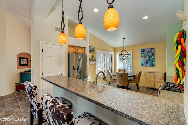 kitchen with lofted ceiling, range, stainless steel fridge with ice dispenser, decorative light fixtures, and kitchen peninsula