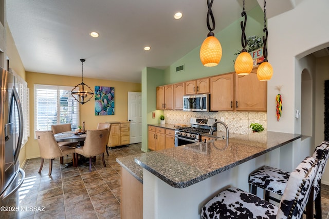 kitchen featuring stainless steel appliances, tasteful backsplash, kitchen peninsula, and decorative light fixtures