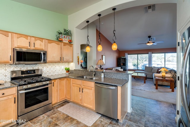 kitchen with appliances with stainless steel finishes, light brown cabinetry, sink, hanging light fixtures, and kitchen peninsula