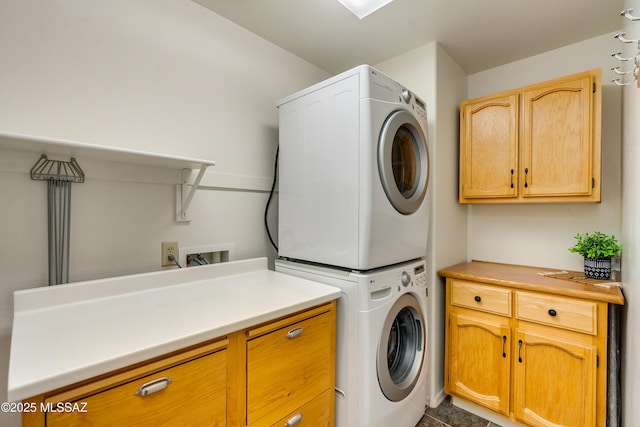 laundry area featuring cabinets and stacked washing maching and dryer