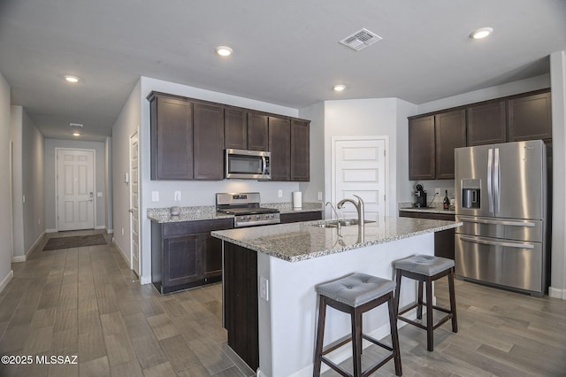 10139 N Sand Sage Trl, Marana, AZ 85653 - kitchen featuring sink, a breakfast bar, appliances with stainless steel finishes, light stone countertops, and an island with sink