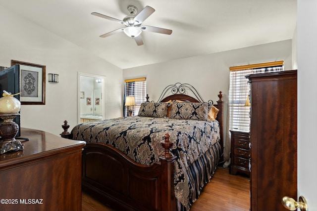 bedroom with hardwood / wood-style flooring, ceiling fan, lofted ceiling, and connected bathroom