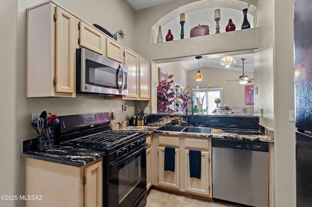 kitchen with ceiling fan, appliances with stainless steel finishes, sink, and dark stone countertops