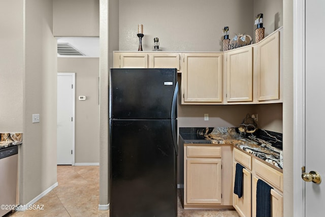 kitchen featuring light tile patterned flooring, black fridge, stainless steel dishwasher, and light brown cabinetry