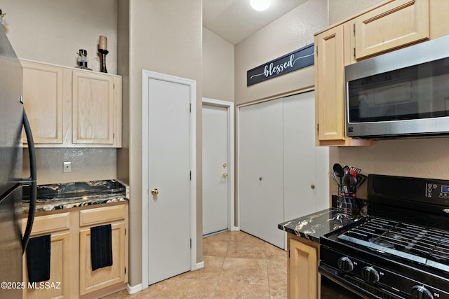 kitchen featuring dark stone counters, light brown cabinets, and black appliances