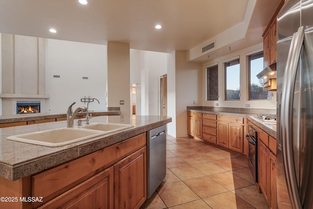 kitchen featuring a kitchen island with sink, sink, light tile patterned flooring, and appliances with stainless steel finishes