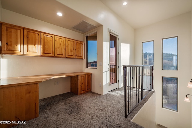 home office with built in desk and dark colored carpet