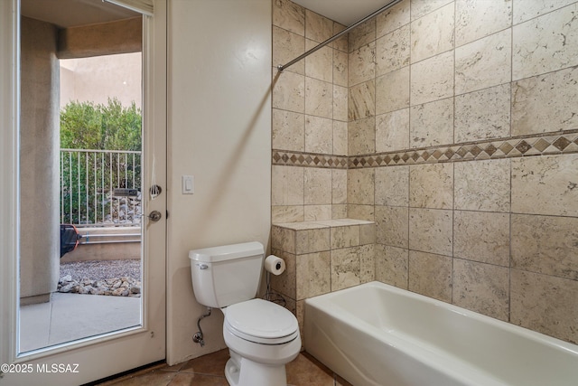 bathroom featuring tile patterned flooring, tiled shower / bath, and toilet