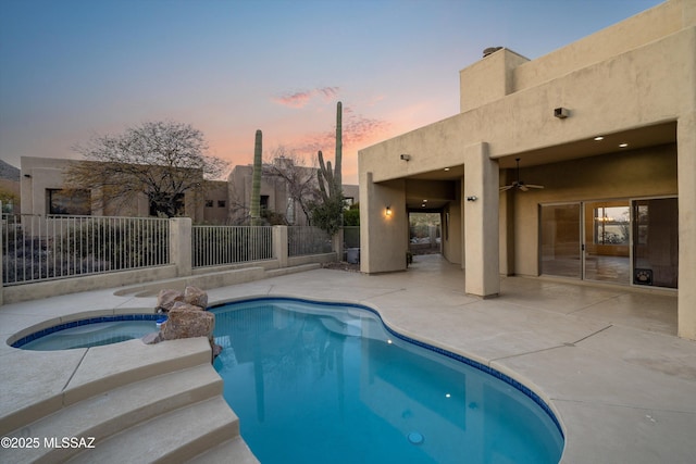 pool at dusk with an in ground hot tub, ceiling fan, and a patio area