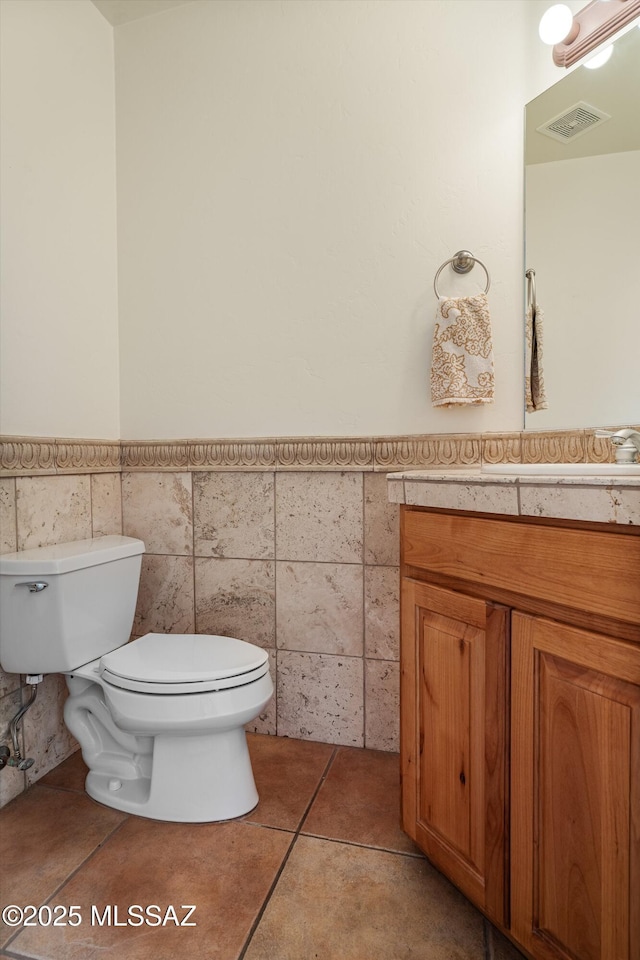 bathroom with vanity, tile walls, tile patterned floors, and toilet