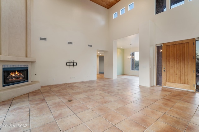 unfurnished living room with a notable chandelier, light tile patterned floors, a fireplace, and wooden ceiling