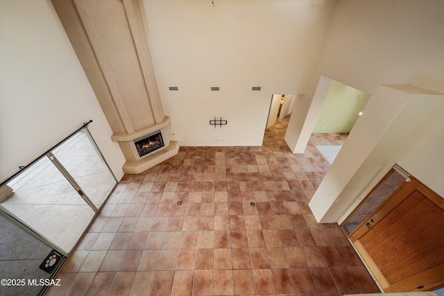 washroom featuring light tile patterned floors, a towering ceiling, and a large fireplace