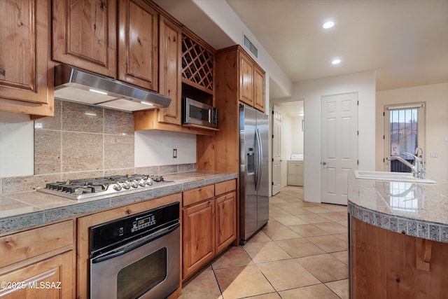 kitchen featuring stainless steel appliances, sink, decorative backsplash, and light tile patterned floors