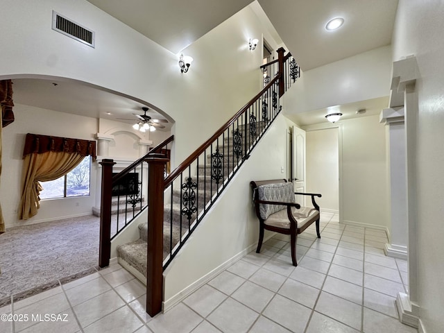 stairway featuring ceiling fan, tile patterned floors, and a towering ceiling