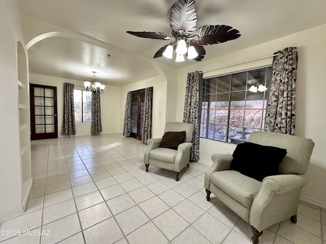 sitting room with light tile patterned floors and ceiling fan with notable chandelier