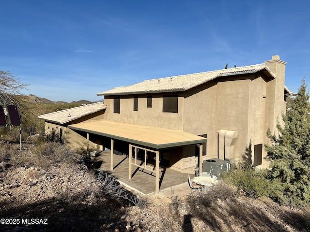 rear view of house with a mountain view and a patio area