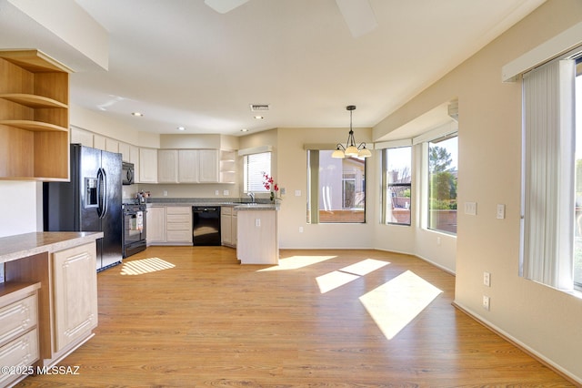 kitchen featuring sink, a notable chandelier, pendant lighting, light hardwood / wood-style floors, and black appliances