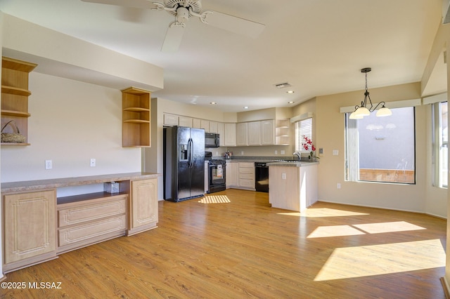 kitchen featuring decorative light fixtures, light brown cabinets, light wood-type flooring, and black appliances