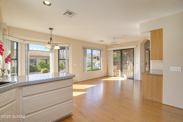 kitchen with pendant lighting, ceiling fan with notable chandelier, light hardwood / wood-style floors, and light brown cabinets