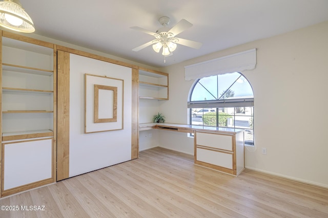 interior space with ceiling fan, built in desk, and light wood-type flooring