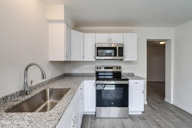 kitchen featuring sink, light stone countertops, white cabinets, and appliances with stainless steel finishes