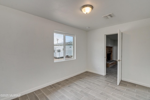 empty room with a brick fireplace and light hardwood / wood-style floors