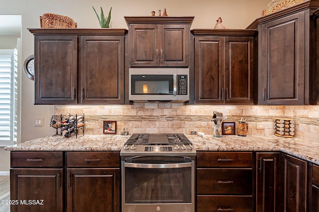 kitchen with tasteful backsplash, appliances with stainless steel finishes, dark brown cabinets, and light stone counters