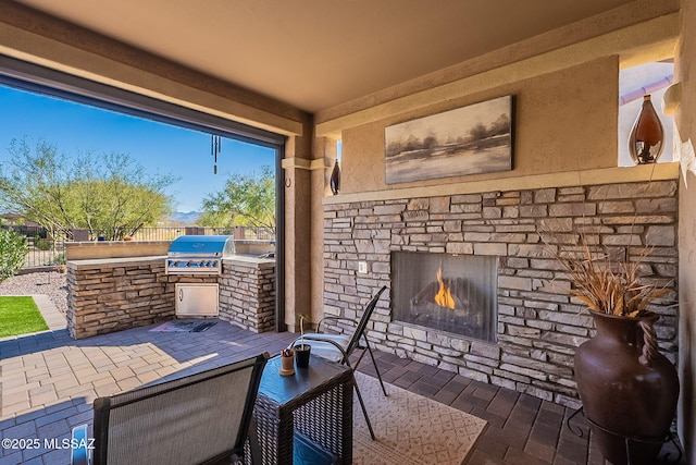 view of patio with a grill, area for grilling, and an outdoor stone fireplace