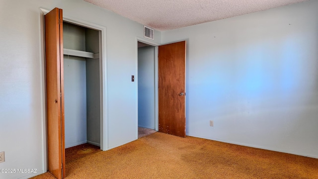 unfurnished bedroom with light colored carpet, a closet, and a textured ceiling