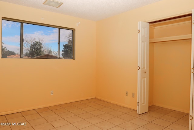 unfurnished bedroom with light tile patterned floors and a textured ceiling