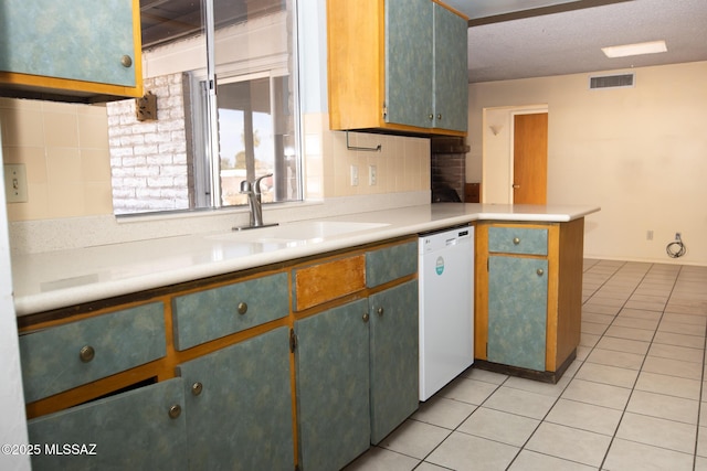 kitchen featuring tasteful backsplash, dishwasher, sink, light tile patterned floors, and a textured ceiling