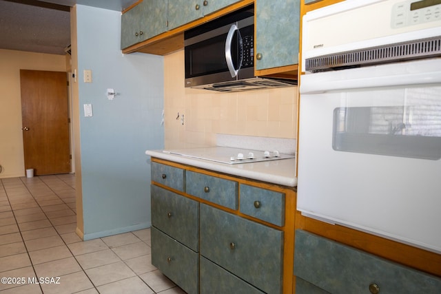 kitchen featuring light tile patterned flooring, white appliances, and decorative backsplash