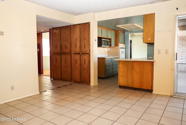 kitchen with tasteful backsplash, light tile patterned flooring, oven, and a textured ceiling