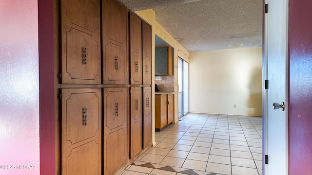 hall with light tile patterned floors and a textured ceiling