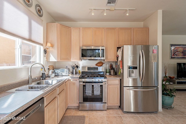 kitchen with light brown cabinetry, sink, light tile patterned flooring, and appliances with stainless steel finishes