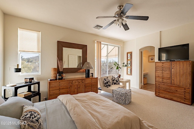 bedroom with light carpet, ensuite bath, and ceiling fan