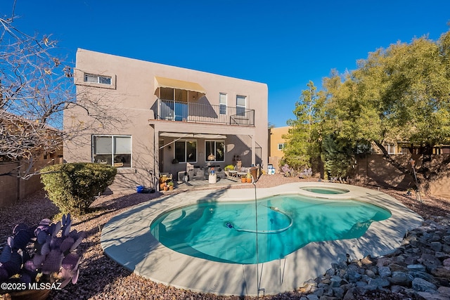 rear view of property featuring a balcony, a pool with hot tub, and a patio area